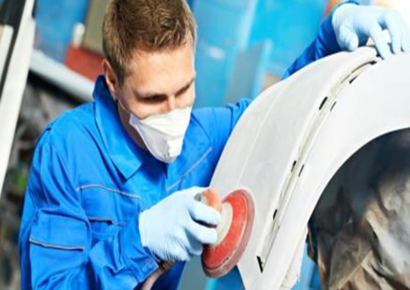 Technician sanding a vehicle fender during auto body repair