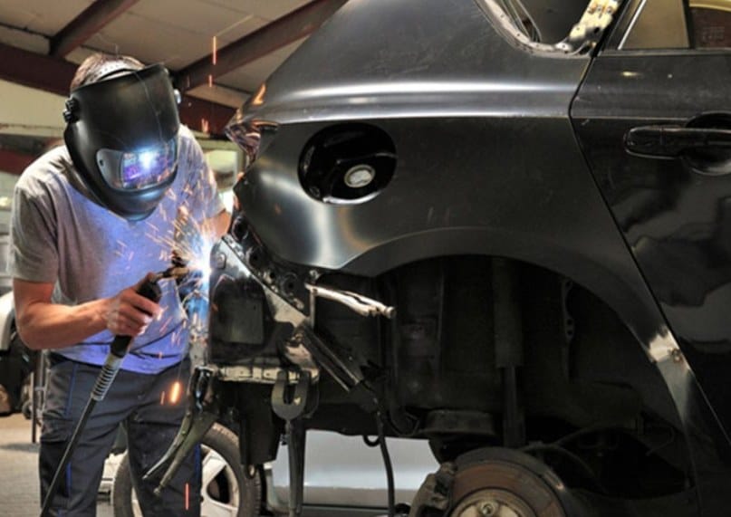 Technician welding a vehicle’s rear body structure during collision repair